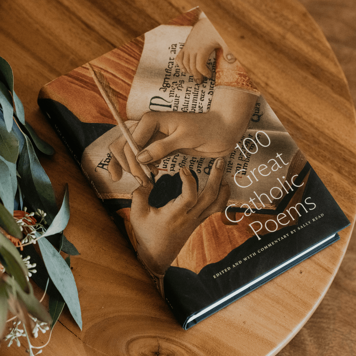 100 Great Catholic Poems book with a cover illustration of hands writing on parchment, edited by Sally Read, book of Catholic poetry, Word on Fire, hardcover 9781685780746