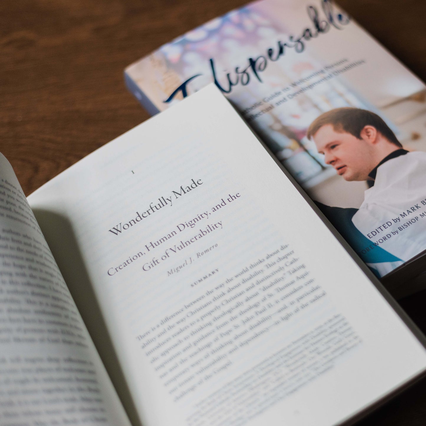 Open book showing a chapter titled "Wonderfully Made: Creation, Human Dignity, and the Gift of Vulnerability" alongside a copy of the book Indispensable, paperback 9781685782207