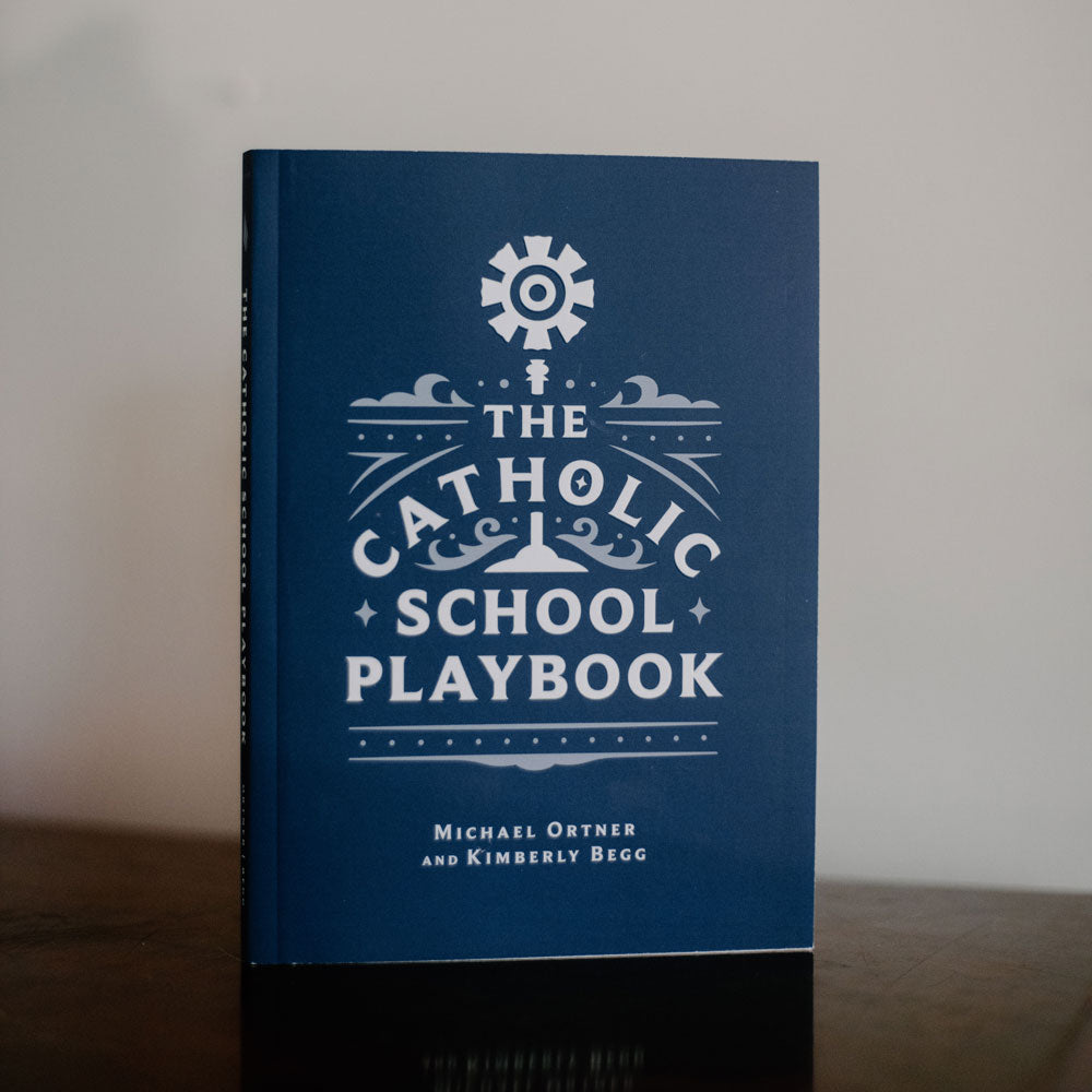 The Catholic School Playbook book cover in blue with white text and design, authored by Michael Ortner and Kimberly Begg, paperback 9781685782085