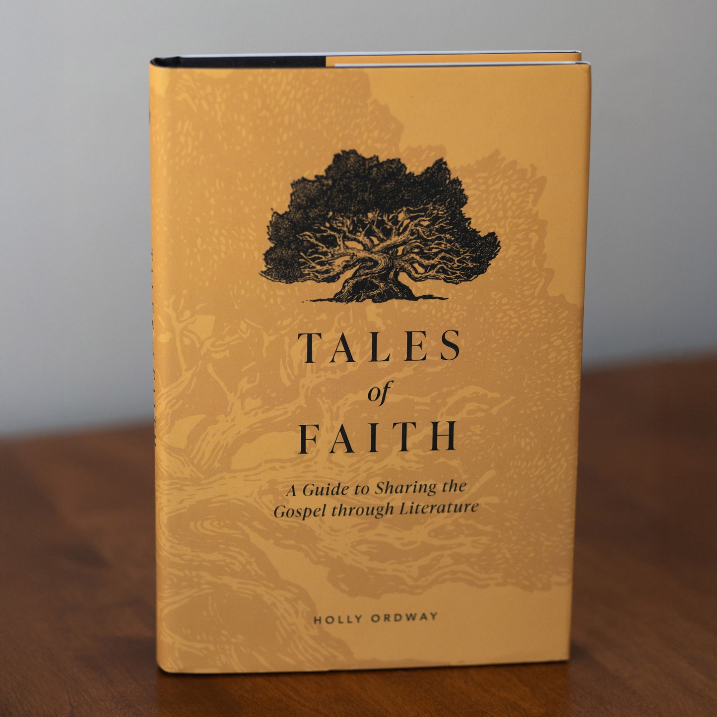 Book with a yellow cover titled "Tales of Faith: A Guide to Sharing the Gospel through Literature" by Holly Ordway, depicting a tree illustration, hardcover 9781685780128