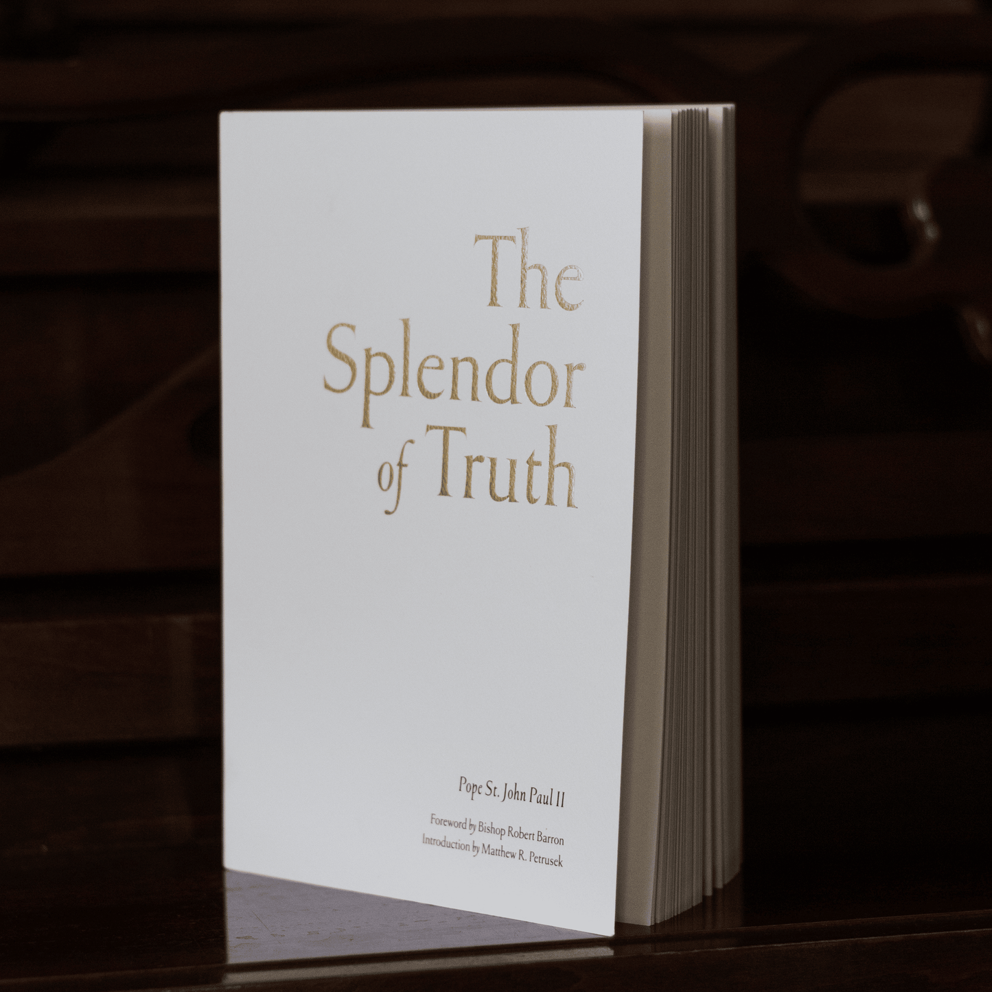 The Splendor of Truth book standing upright with a plain white cover and gold and black text, featuring contributions by Pope St. John Paul II, Bishop Robert Barron, and Matthew R. Petrusek, suitable for spiritual growth, paperback 9781685781675
