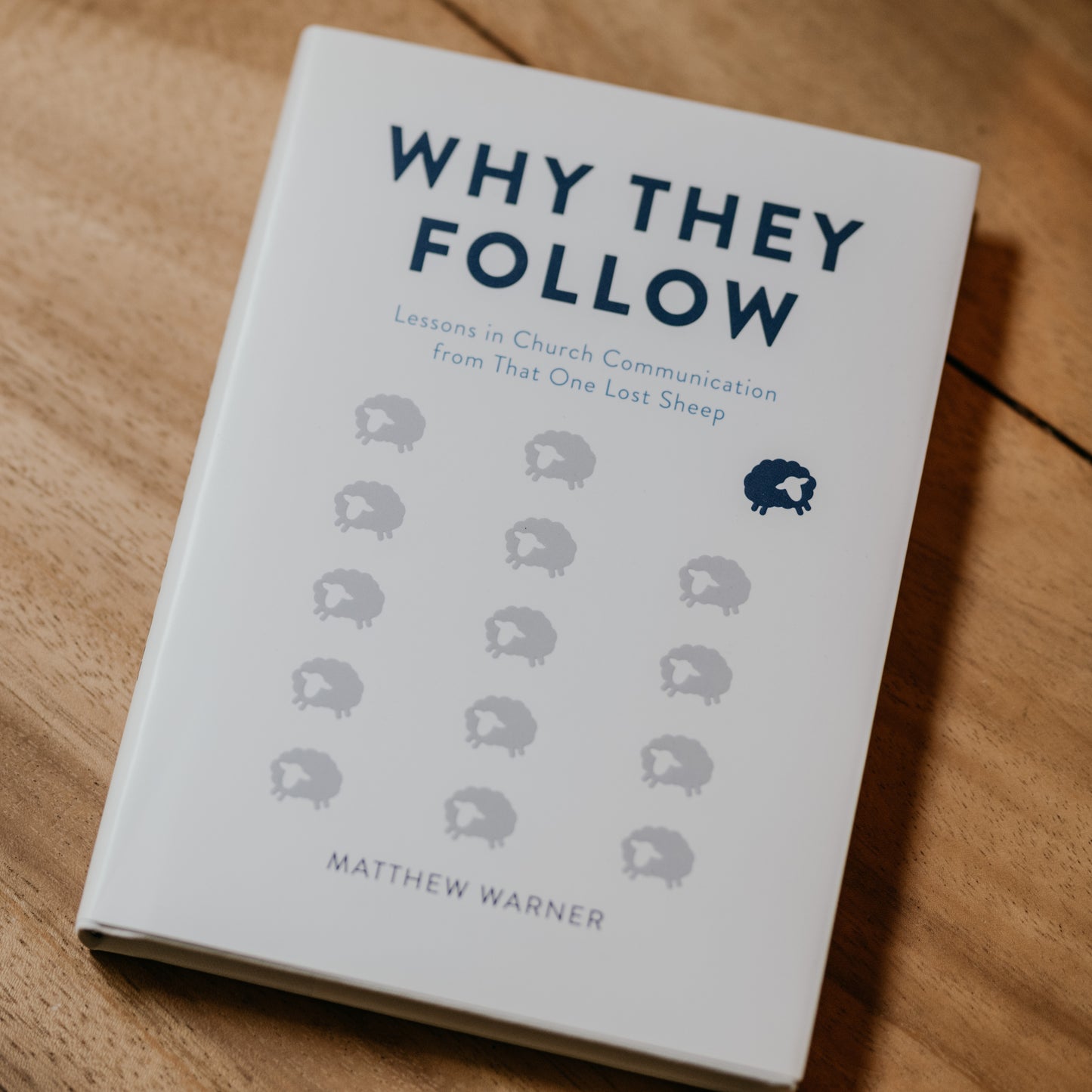 Book cover of "Why They Follow" by Matthew Warner, featuring a minimalist design with a group of gray sheep and one black sheep, focused on church communication and evangelization, books for Catholic parishes, hardcover 9781685780401