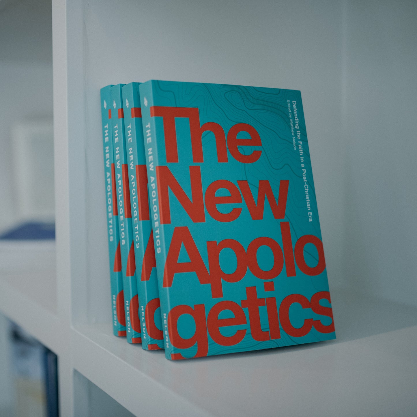Stack of books titled The New Apologetics, Catholic book for evangelization, authored by multiple contributors including Matthew Nelson and Thomas Collins, paperback 9781685780043