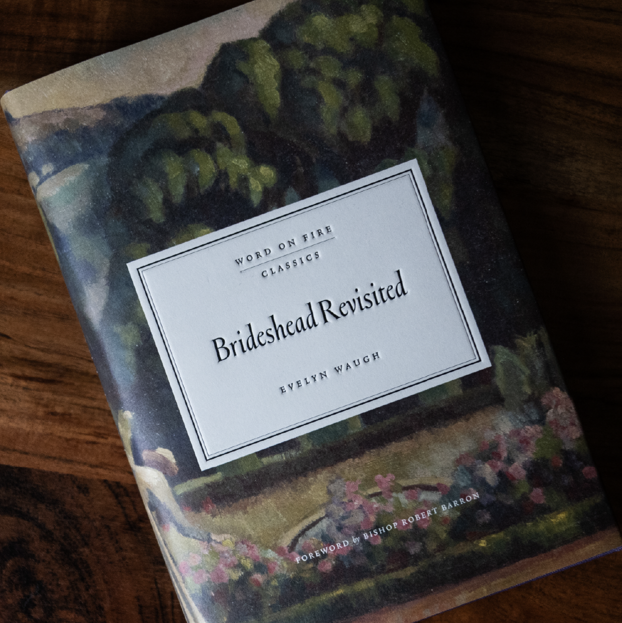 Book titled Brideshead Revisited by Evelyn Waugh from Word on Fire Classics with a foreword by Bishop Robert Barron, lying on a wooden surface, classic novel, hardcover 9781685782382
