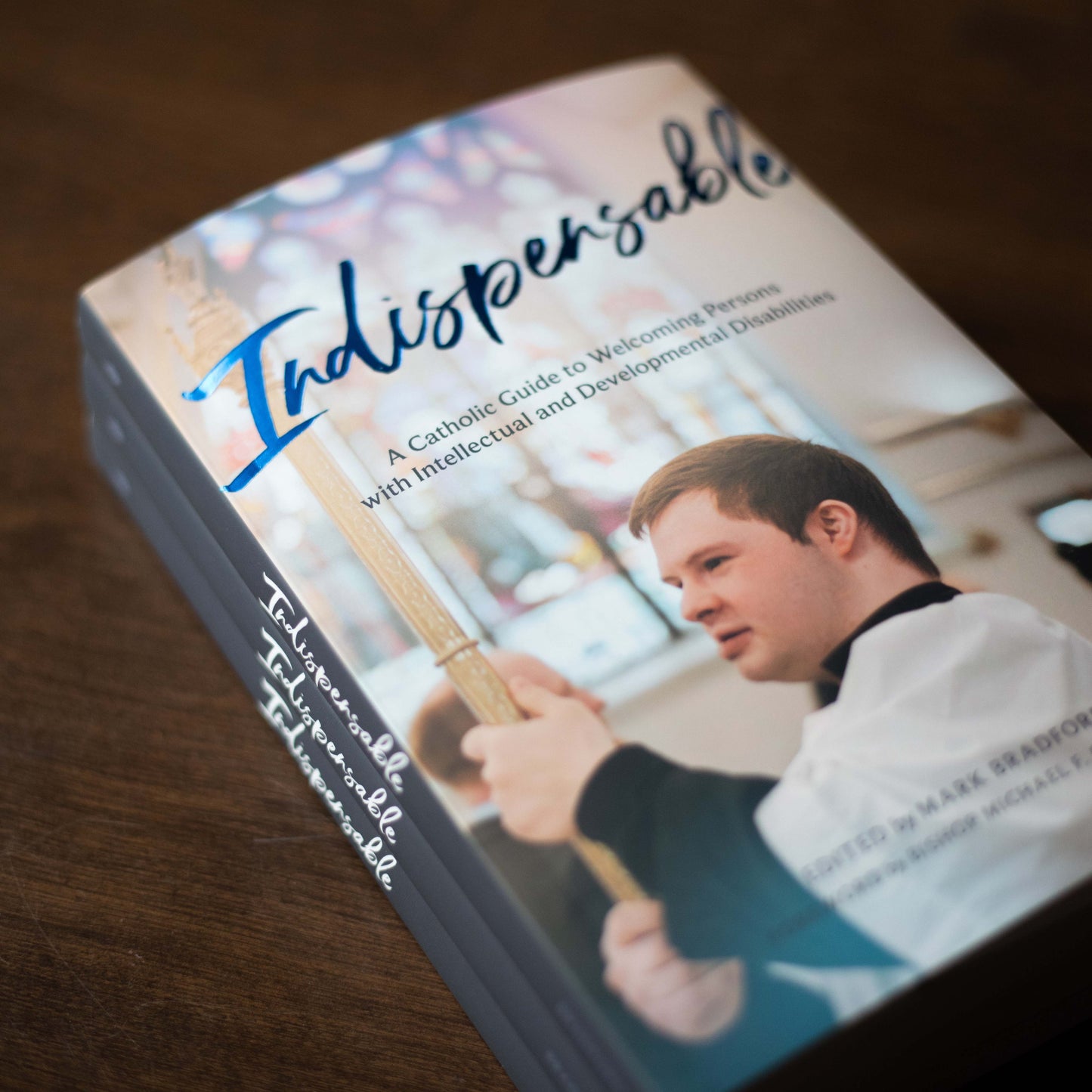 Stack of "Indispensable" books featuring a young man altar serving in a church setting, by Mark Bradford, paperback 9781685782207