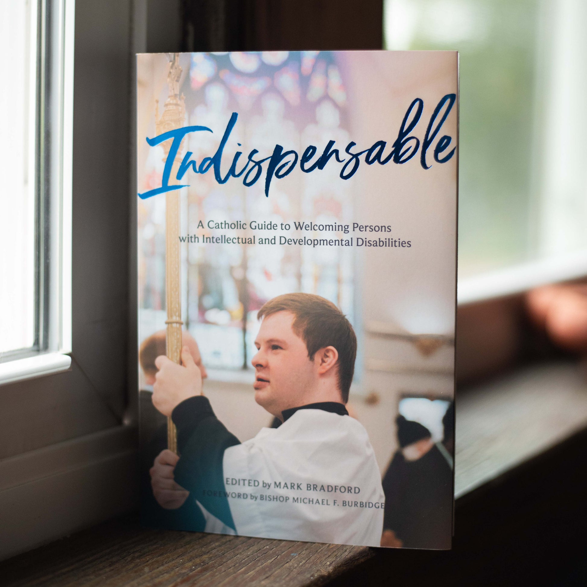 Indispensable book cover showing a young man with Down Syndrome altar serving in a Catholic parish, by Mark Bradford, paperback 9781685782207