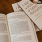 Open book displaying text on Saint Augustine's theology with two "I Am a Son of Saint Augustine" books on a table, paperback 9781685783198