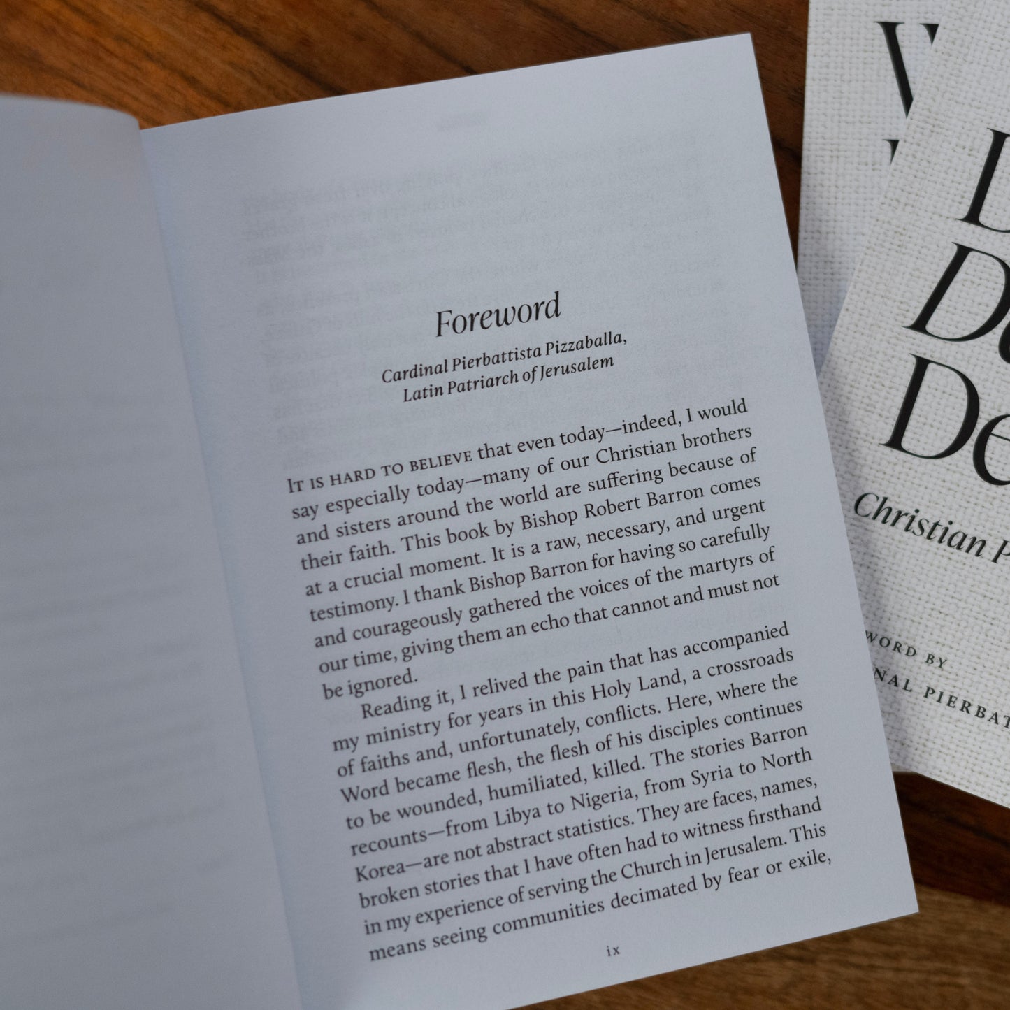 Open book page showing the foreword by Cardinal Pierbattista Pizzaballa, Latin Patriarch of Jerusalem, in the Catholic book "What Do Their Deaths Demand?", a prayer and theology book contributed by Christian authors, suitable for adult readers, paperback edition, 9781685783754