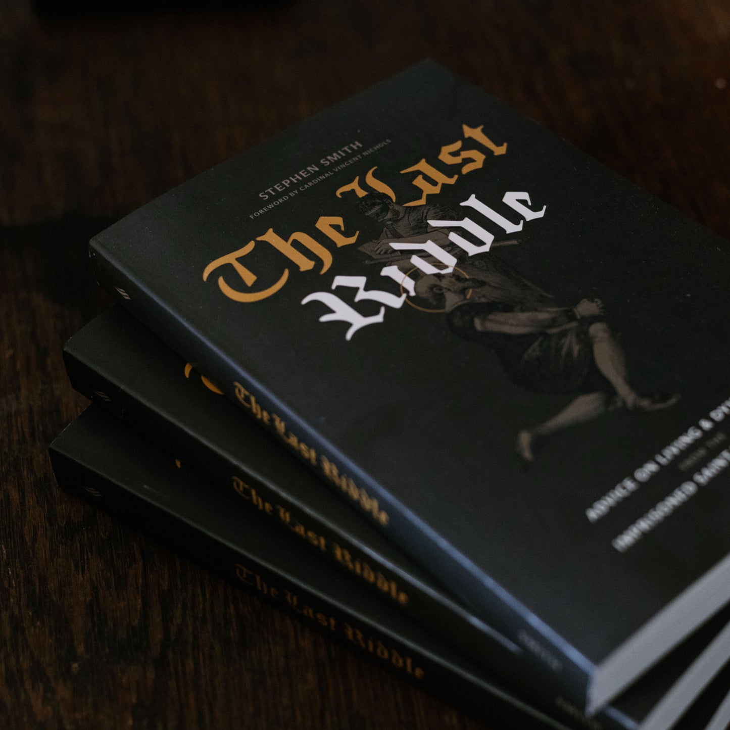 Stack of books titled 'The Last Riddle' on a dark surface
