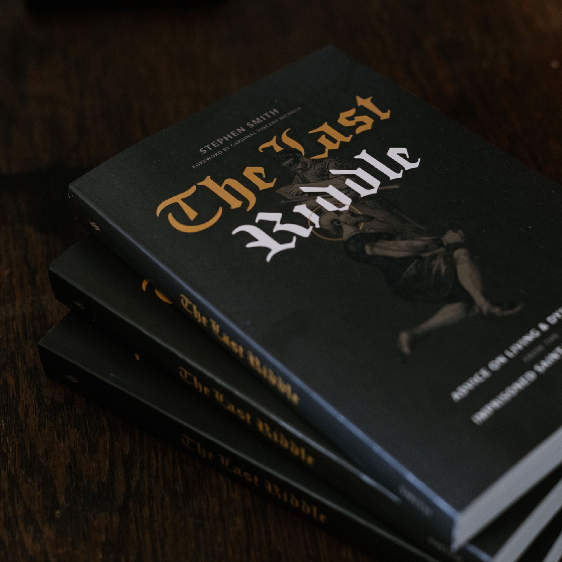 Stack of books titled 'The Last Riddle' on a dark surface