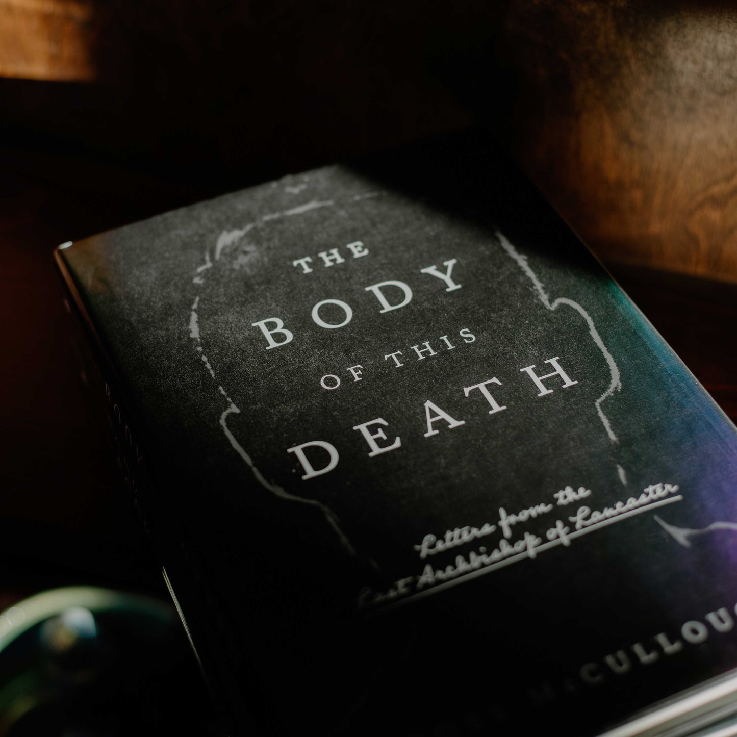 The Body of This Death book with a dark cover featuring a subtle silhouette and white text, hardcover 9781685782597
