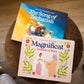 Two illustrated Catholic children’s books lying on a wooden table, titled The Song of Zechariah and Magnificat Canticle of Mary, featuring vibrant cover art, for ages 1-5, helping babies and toddlers pray with scripture