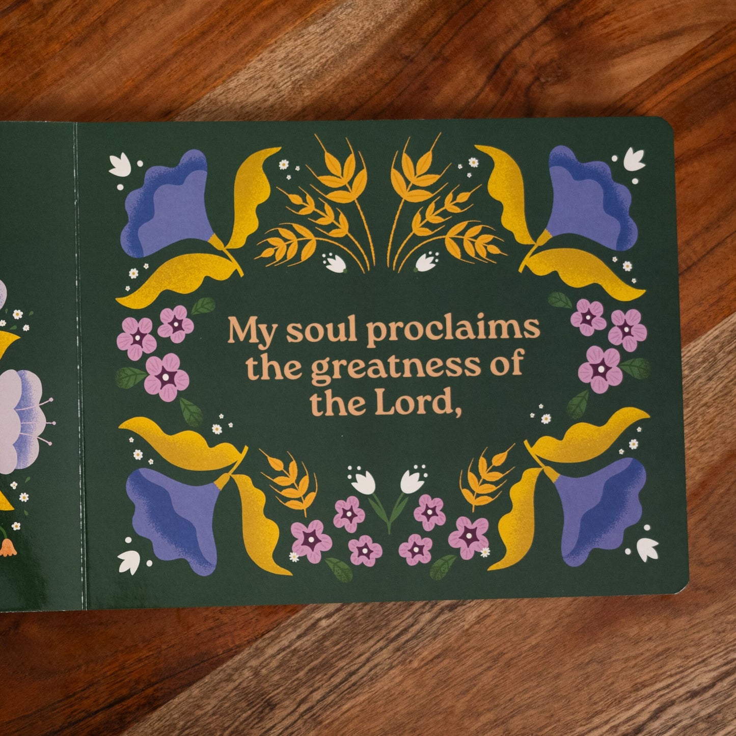 Open page from Magnificat Canticle of Mary featuring colorful floral illustrations surrounding the text "My soul proclaims the greatness of the Lord," illustrated by Tricia Dugat, board book 9781685781521
