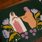 Illustration from Magnificat Canticle of Mary featuring the visitation of Mary to her cousin Elizabeth, biblical scene surrounded by purple and white flowers, for babies and toddlers ages 1-5, board book 9781685781521
