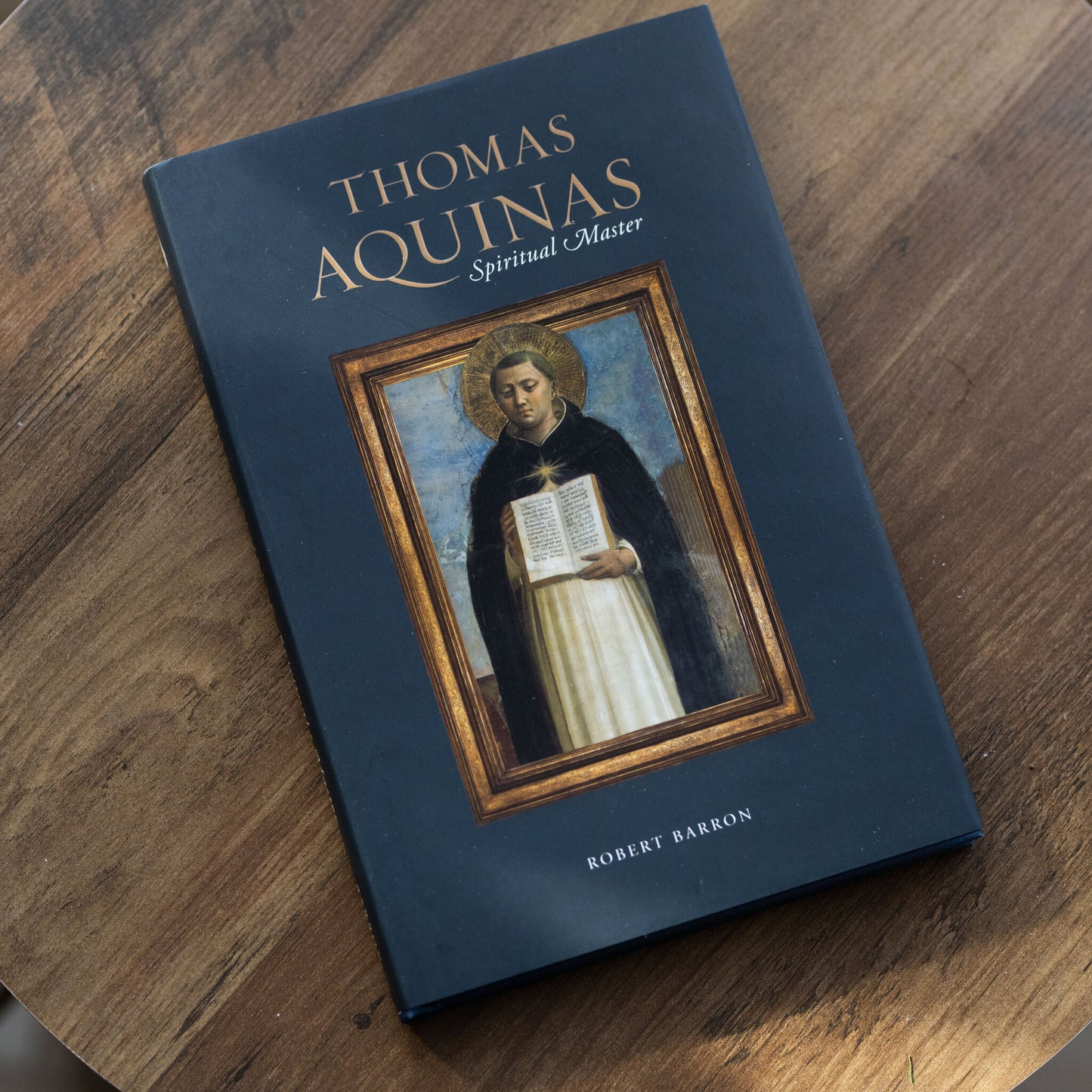Thomas Aquinas: Spiritual Master book cover on a wooden table, published by Word on Fire Academic, written by Bishop Robert Barron, theology book for Catholics, hardcover 9781943243792