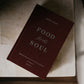 A maroon hardcover book titled "Food for the Soul - Cycle C" by Peter Kreeft rests on a light-colored surface, featuring reflections on the daily Mass readings for spiritual growth and evangelization